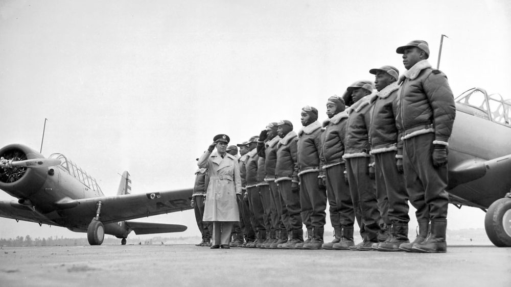 The Tuskegee Airmen stand at attention as Major James A. Ellison returns the salute of Mac Ross, one of the first graduates of the Tuskegee cadets. The photographs shows the pride and poise of the Tuskegee Airmen, who continued a tradition of African Americans honorably serving a country that still considered them second-class citizens.