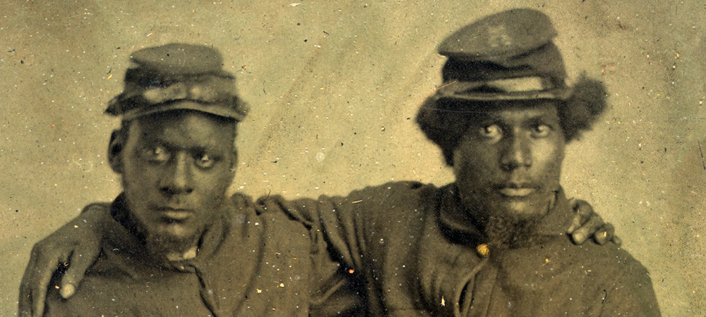Two black men in uniform with their arms around each other's shoulders.