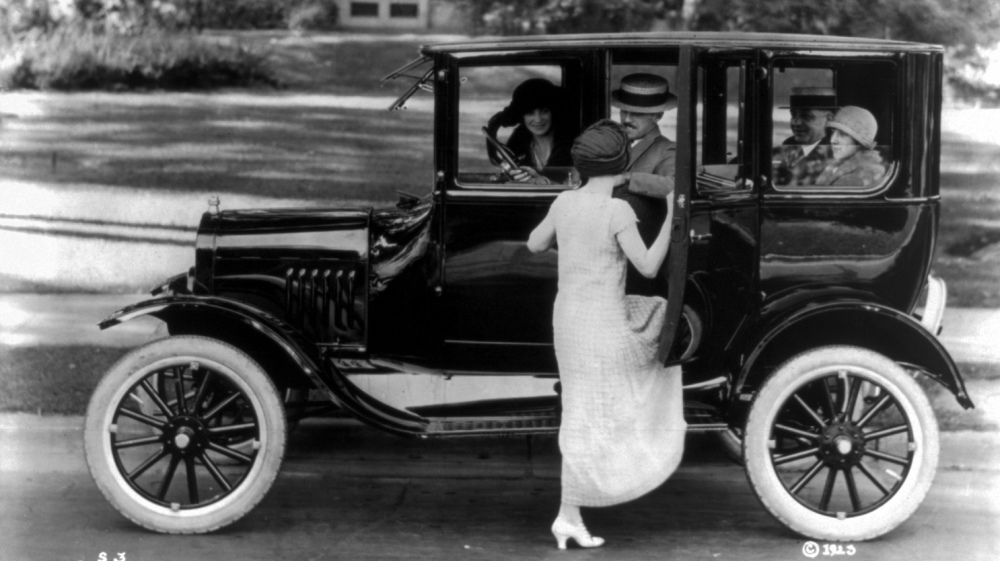 Side view of a Ford sedan with four passengers and a woman getting in on the driver's side, ca.1923. Library of Congress, LC-USZ62-54096.