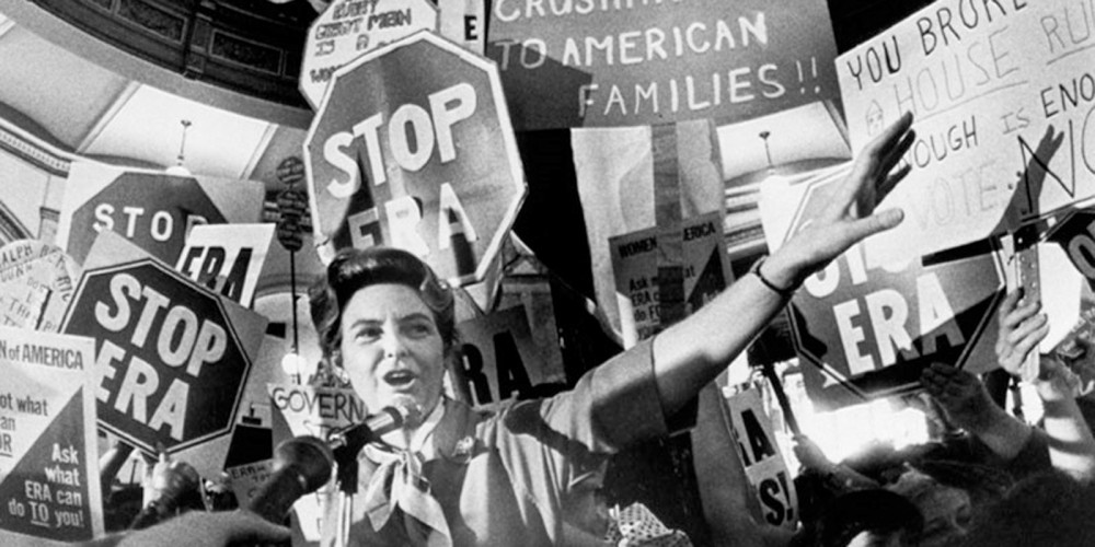 Photograph of the activist Phyllis Schlafly campaigning against the Equal Rights Amendment in 1978. She stands in front of stop signs that say "STOP ERA" 