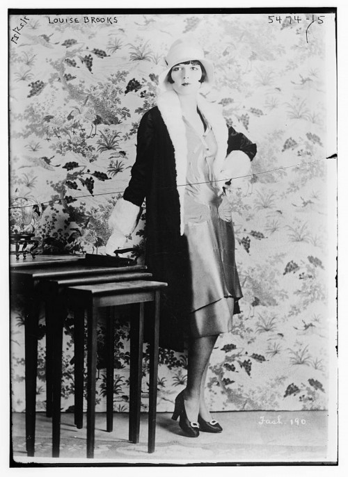 Photograph of a flapper with bobbed hair and a dress just below her knee. 