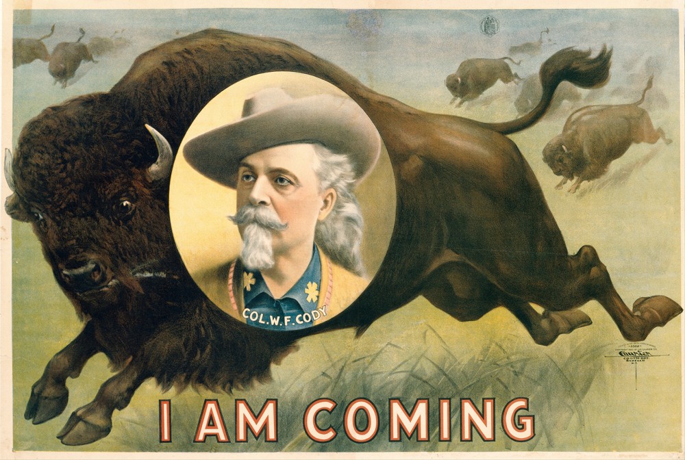 This advertisement for William Frederick “Buffalo Bill” Cody's show has a charging buffalo and Cody's face in a vignette with the words "I am Coming" at the bottom.