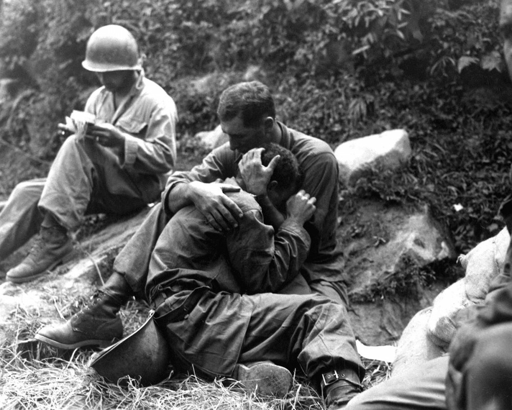 Photograph of a soldier embracing and comforting another soldier.