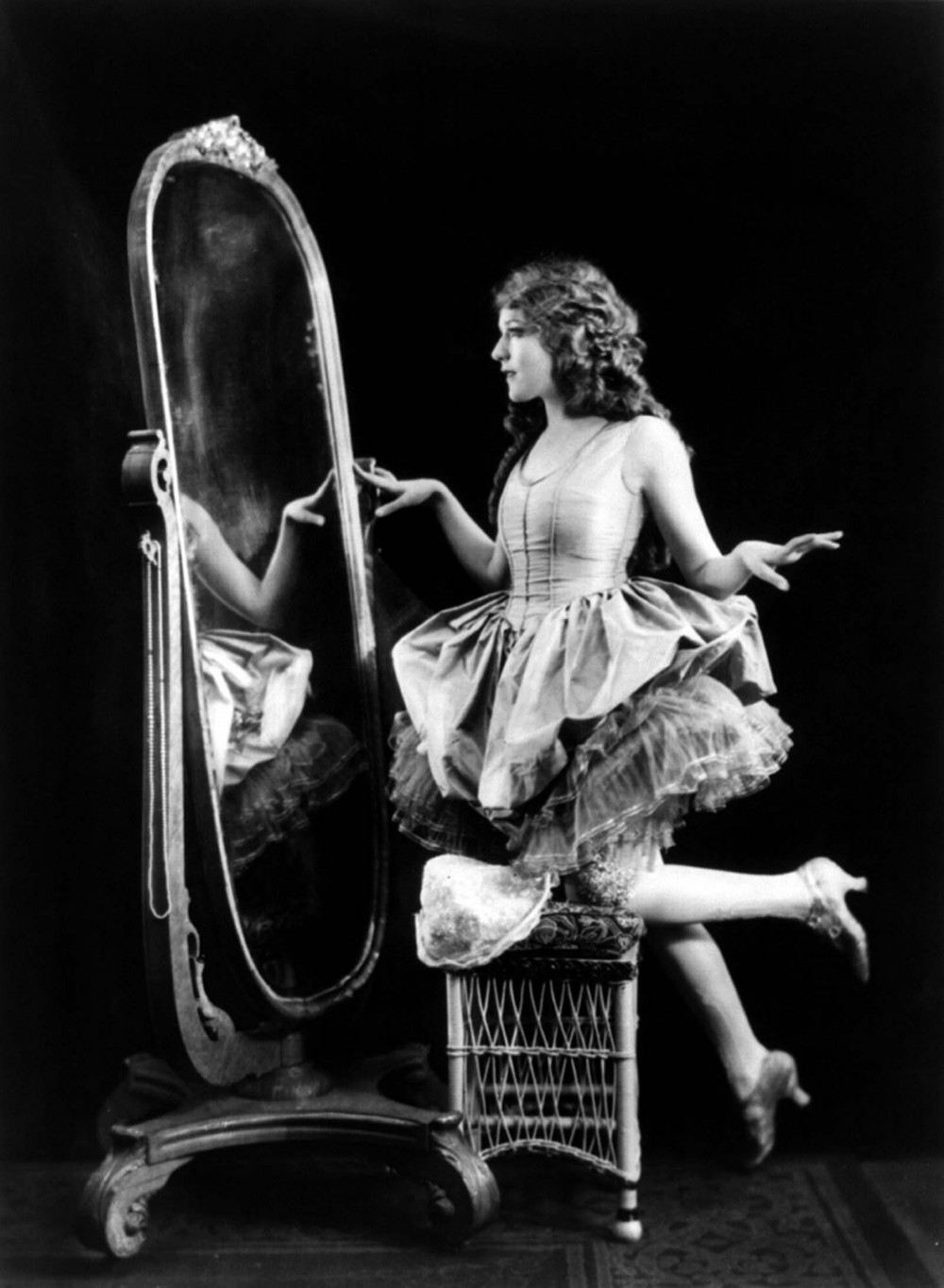 Photograph of the glamorous Mary Pickford posing in front of a mirror. 