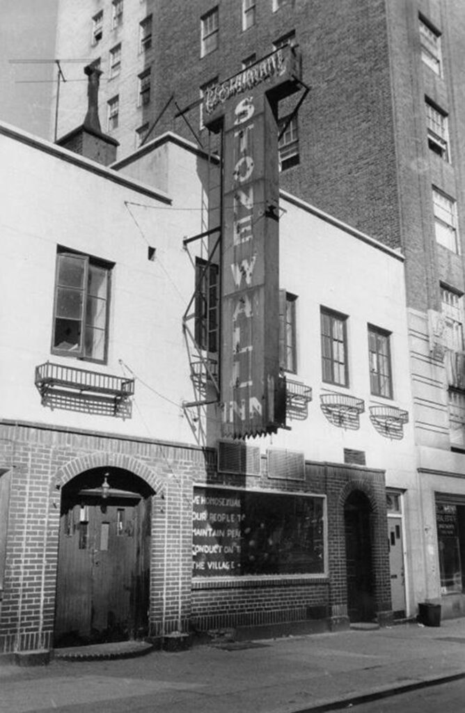 A picture of the Stonewall Inn. A sign in the window reads: “We homosexuals plead with our people to please help maintain peaceful and quiet conduct on the streets of the Village–Mattachine.” 
