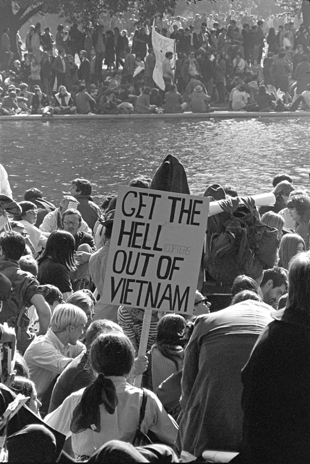 A crowd of protestors; one is holding a sign reading “Get the Hell Out of Vietnam.”