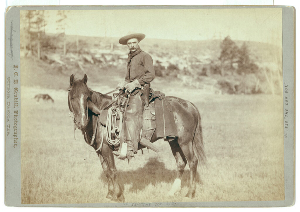A cowboy poses atop a horse.