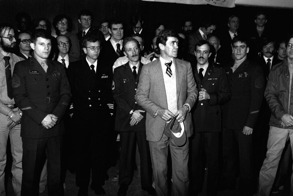 A group of men and women, many in uniform, stand.