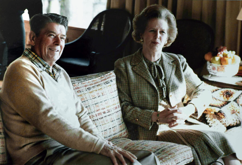 An old man and woman pose on a couch.