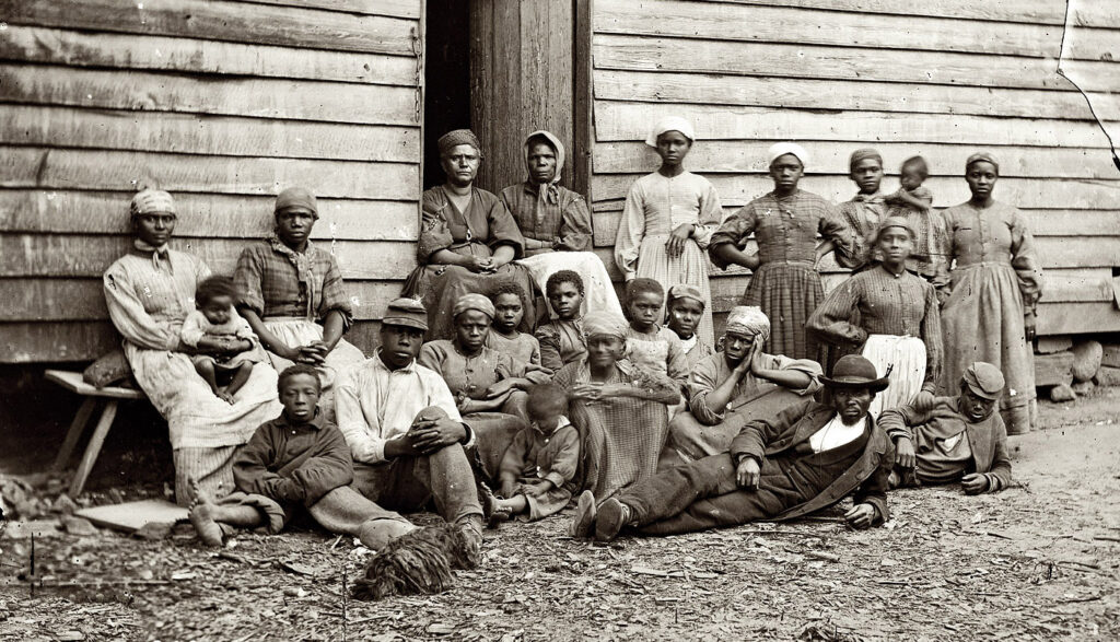 “Contrabands,” Cumberland Landing, Virginia, 1862. Library of Congress. Photograph of over a dozen African Americans sitting or standing in front of a cabin. They range in age from children to the elderly. 