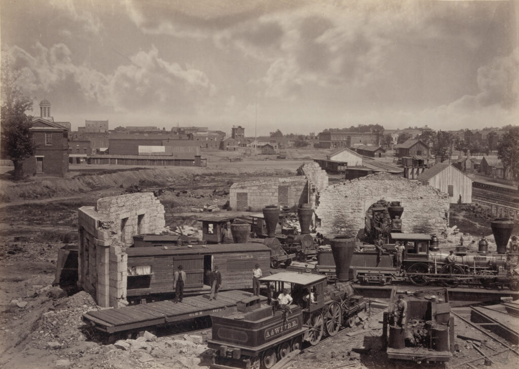 A photograph of destroyed buildings and railroad cars in Atlanta. George N. Barnard, City of Atlanta, Ga., no. 1, c. 1866. Library of Congress.