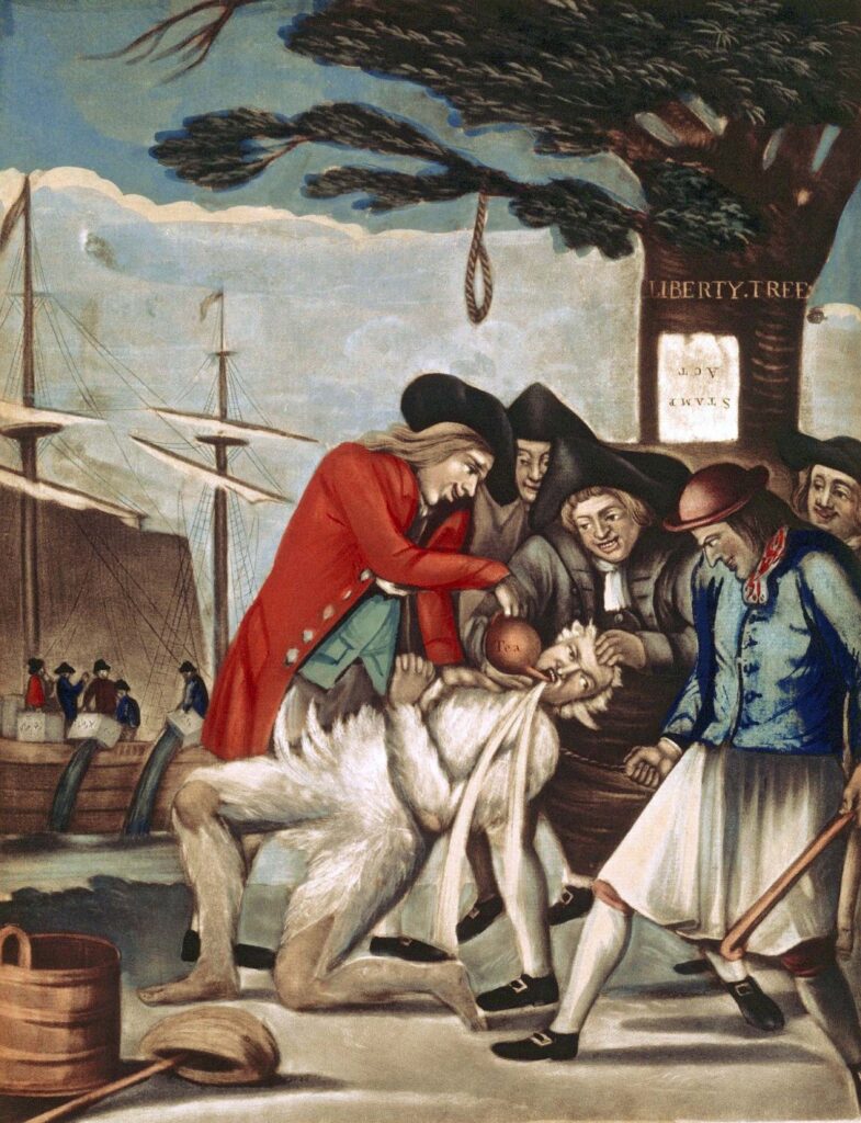 Five men, members of the Sons of Liberty are tarring and feathering Boston’s Commissioner of Customs, John Malcolm. The Sons of Liberty are dressed in traditional eighteenth-century British colonial attire—shirts, breeches, waistcoats, coats, stockings, shoes, and caps. Malcolm’s body is covered in white feathers. One of the Sons of Liberty is holding Malcolm by the top of his head and his jaw, forcing his mouth open, while another pours hot molasses into Malcolm’s mouth. The other three Sons of Liberty are huddled around the action, looking on menacingly; one of which is holding a baton. In the immediate background there is a tree with a noose behind the Sons of Liberty. A piece of paper with the words “Stamp Act” is nailed to the tree upside-down. The words “Liberty Tree” are carved into the tree above the piece of paper. Farther in the background is the Boston Habor, where other men can be seen on a ship docked in the harbor; the men are pouring tea from boxes into the waters of the harbor.