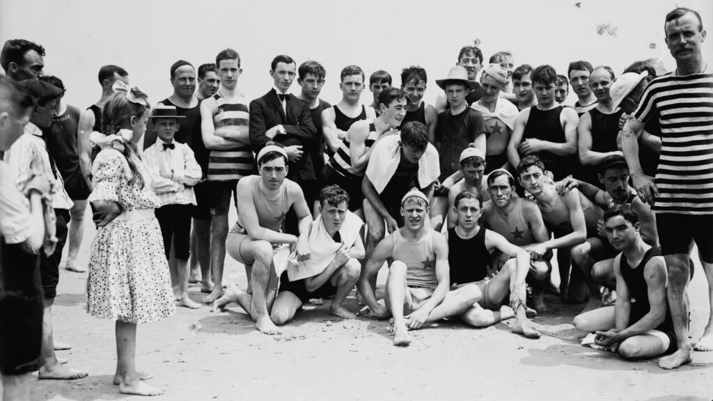 Young men pose on a beach.